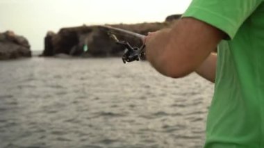 Balıkçı oltayı denize atar ve alır, balık tutma tekniği, yakın plan çekimler ve makaralar..