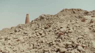 Pakistan 'da köle işçi çalıştıran bir tuğla fabrikası. Kumda boş bir karavan var. Arka planda duman olan büyük tuğla pipo. Yavaş çekim