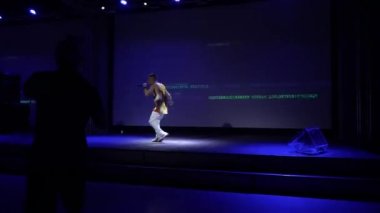 Moskova, Rusya - 25 Mayıs 2021: DJ partisi. Genç enerjik bir rap müzisyeni bir gece kulübünün sahnesinde şarkı söylüyor. Seyirci sanatçının performansını ve dansını izliyor. Sahne ışıkları parlıyor. 4K Görüntü