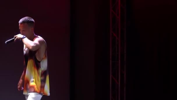 Москва, Россия - 25 мая 2021 года: фестиваль рэпа. Молодой энергичный рэп-музыкант поет и танцует на сцене ночного клуба. Прожектор светит. 4K Footage — стоковое видео