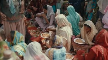Karachi, Pakistan - Eylül 2021. Zavallı Pakistanlı kadınlar ve ulusal kıyafetler içindeki kızlar karton tabaklardan elleriyle pilav yiyorlar. Sıcak hava
