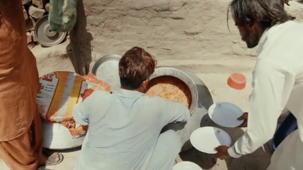 Karachi, Pakistan - settembre 2021. Nutrire poveri senzatetto affamati in Pakistan. Un uomo mette il pilaf nei piatti e lo distribuisce alla gente — Video Stock