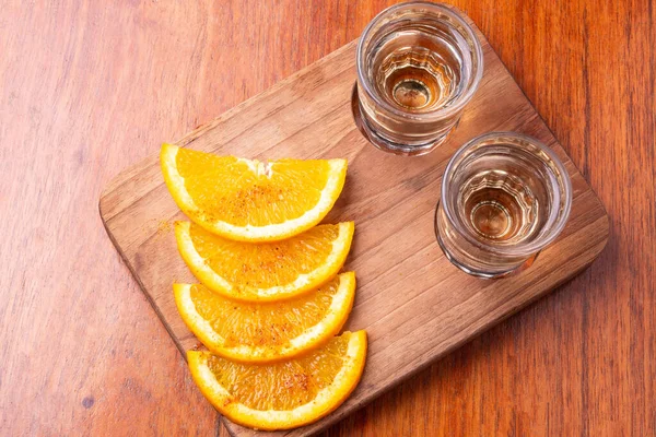 两张夹着橙子片和蠕虫盐的梅兹卡酒的照片放在一张木制桌子上 上面有你的文字 龙舌兰酒墨西哥白兰地的概念 图库图片