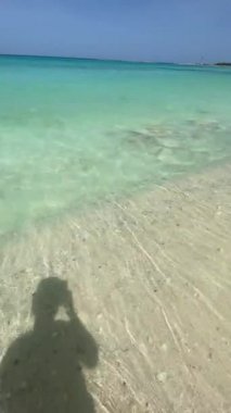 Cell phone video on the shore of the caribbean sea. My shadow reflected in the white sand and the turquoise waters of the sea. vacation concept