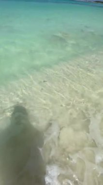 Cell phone video on the shore of the caribbean sea. My shadow reflected in the white sand and the turquoise waters of the sea. vacation concept
