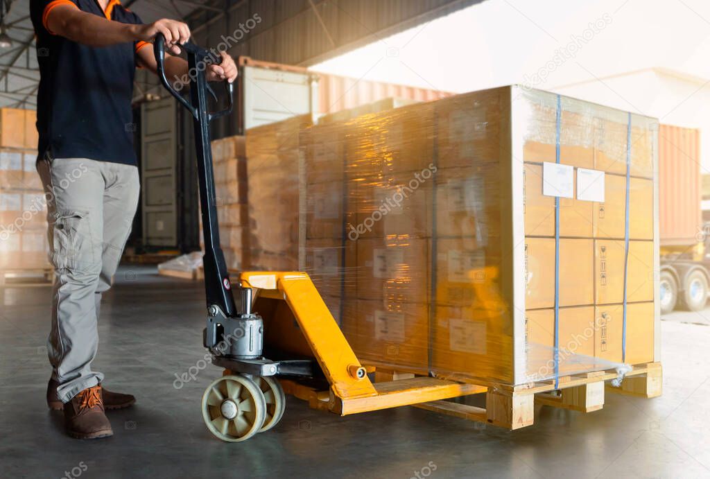 Workers Using Hand Pallet Jack Unloading Package Boxes into Cargo Container. Delivery Shipment Boxes. Trucks Loading at Dock Warehouse. Supply Chain. Warehouse Shipping Transport and Logistics.