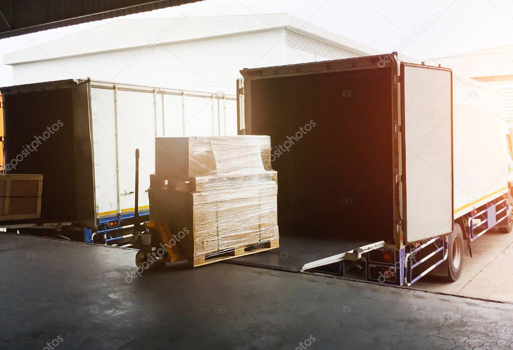 Cargo Package Boxes Loading into Shipping Cargo Container. Trucks Parked Loading at Dock Warehouse. Commece Supply Chain Shipment Logistics Export-Import. Freight Truck Transportation