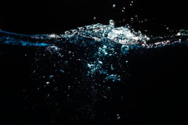 Su sıçraması. Kara Arkaplanda Dalgalanan ve Kabarcıklar Yüzen Su Yüzeyi.