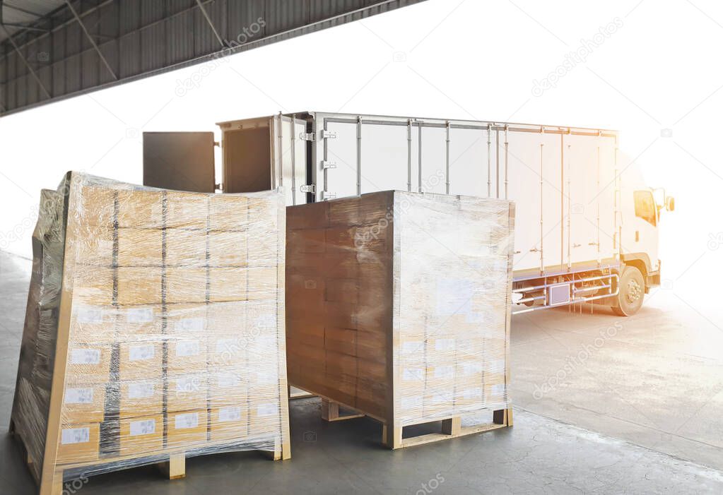 Packaging Boxes on Pallets Loading into Shipping Cargo Container. Delivery Trucks Parked Loading at Dock Warehouse. Supply Chain Customers Shipment Logistics. Cargo Freight Truck Transport.