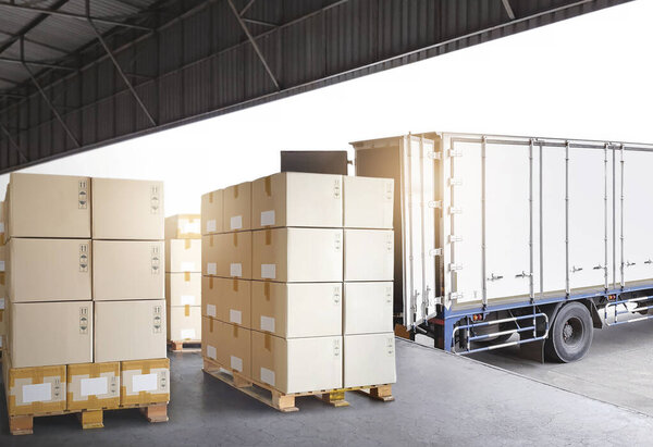 Packaging Boxes Stacked on Pallet Loading into Shipping Cargo Container. Supply Chain. Trucks Parked Loading at Dock Warehouse. Shipment Logistics. Cargo Freight Truck Transport.