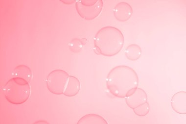 Pembe şeffaf sabun köpükleri havada süzülüyor. Sabun köpüklü su.