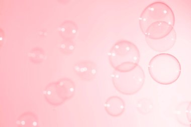 Pembe şeffaf sabun köpükleri havada süzülüyor. Sabun köpüklü su.