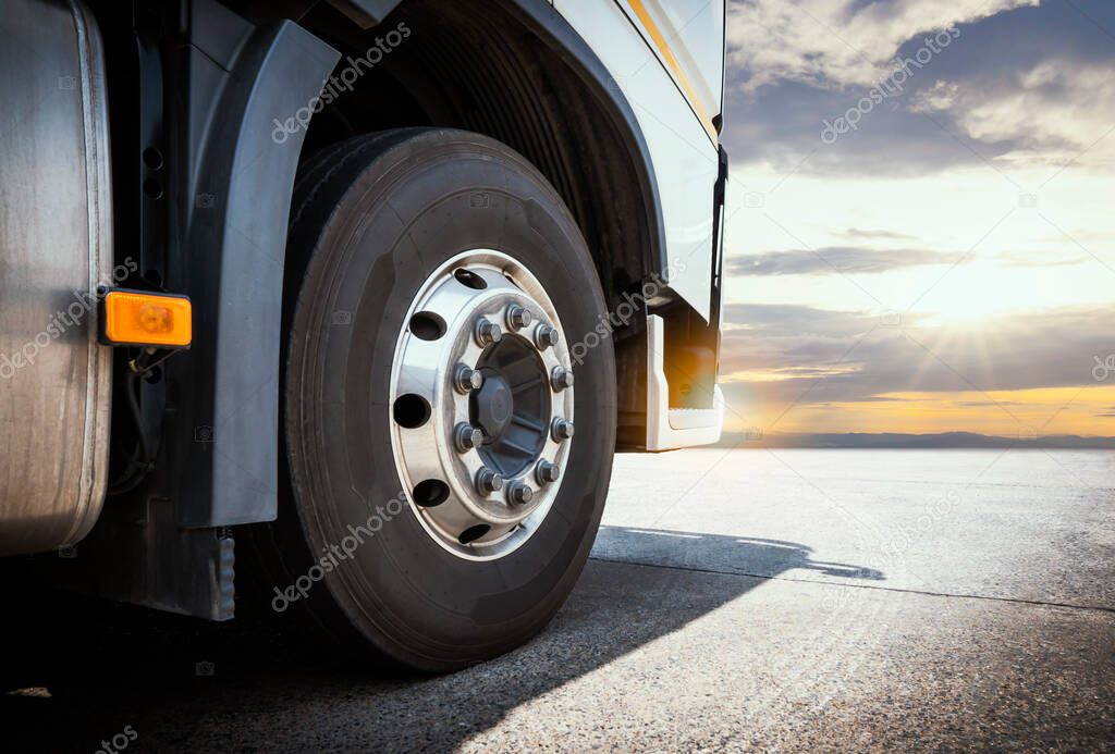 Front Big Rig Semi Truck Wheels Tires. Lorry Tyres Rubber. Trucks Parked with the Sunset. Freight Trucks Cargo Transport Logistics.