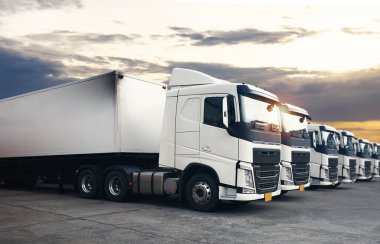 Yarı karavan kamyonları Sunset Sky ile park etmiş. Dizel Kamyon. Kamyonların önü. Nakliye kamyonları. Kamyon Traktörü. Kamyon Lojistik Kargo Taşımacılığı.