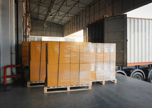 Packaging Boxes Wrapped Plastic on Pallets Loading with Shipping Cargo Container. Trucks Parked Loading at Dock Warehouse. Shipment Supply Chain. Distribution Freight Truck Transport Logistics