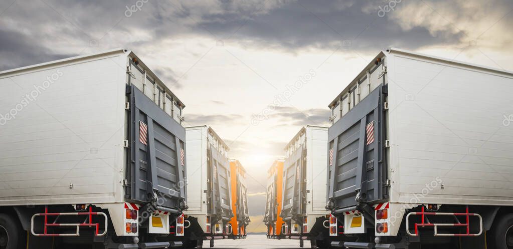 Row of Cargo Container Trucks with Lifting Ramp Parked Lot at the Sunset Sky. Diesel Truck Lorry. Shipping Container Trucks Freight. Distribution Warehouse. Cargo Transport Logistics.