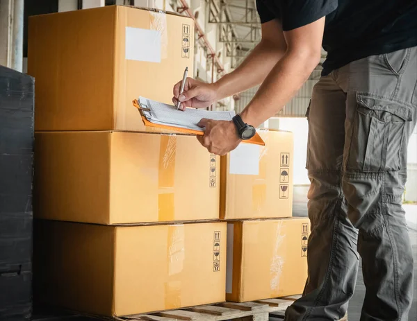 クリップボードを保持している労働者は 倉庫の梱包箱をチェックしています 在庫管理サプライチェーン 出荷箱 配送倉庫物流 — ストック写真