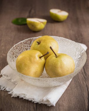 Ahşap zemin üzerinde bir kasede taze sarı armutlar.