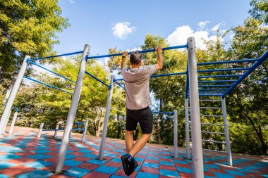  Parktaki yatay bir çubukta egzersiz yapan bir adam. Açık hava sporları.
