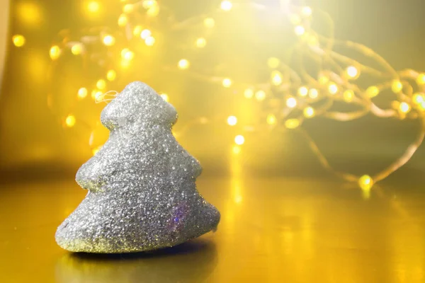 Juguete de Navidad brillante árbol sobre un fondo dorado con luces. —  Fotos de Stock