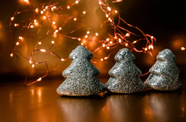 Tres juguetes de navidad brillando árboles sobre un fondo dorado con luces. —  Fotos de Stock