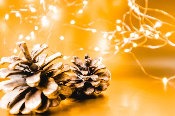 Cones de Natal em um fundo dourado com luzes. Fundo de Natal. 2022 — Fotografia de Stock