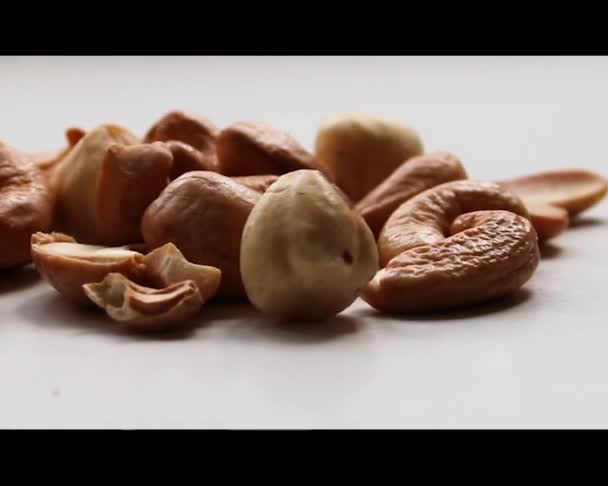 Nötter Cashewnötter och hasselnötter ligger på en vit bakgrund. Flytta kameran åt sidan. — Stockvideo