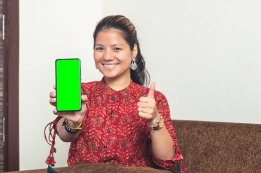 Genç Hintli kız yeşil ekranlı cep telefonunu gösteriyor. Geleneksel giysiler içinde cep telefonlu Hintli bir kız..