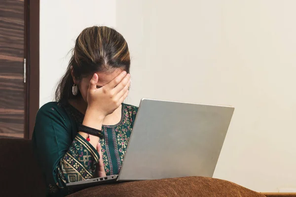 Genç Hintli işçi kız dizüstü bilgisayarı üzerinde çalışırken baş ağrısı çekiyor. Evde yalnız başına çaresizlik çekiyor. Mutsuz, binlerce yıllık Hint kökenli kadının elinde yüzünü saklaması, hayat sıkıntısı ya da baş ağrısı çekmesi..