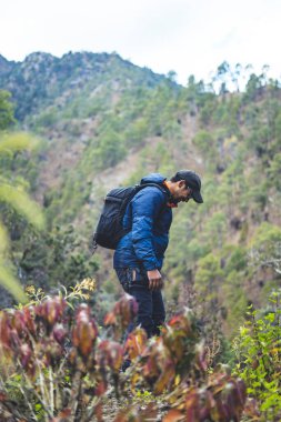 Hipster young boy with backpack enjoying trekking sunset on the mountains. Tourist traveler on background valley landscape view mockup.