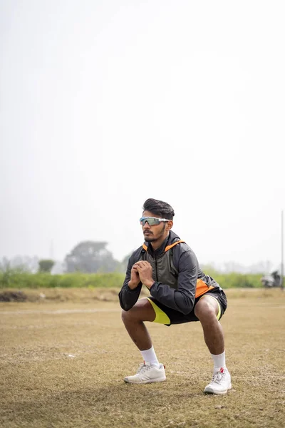 若いインドのスポーツマンが野球場でスクワットをしている スポーツと健康的なライフスタイルのコンセプト — ストック写真