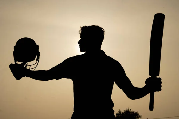 Kriket maçında bir yüzyıl geçirdikten sonra kutlama yapan bir kriket oyuncusunun silueti. Hint kriket oyuncuları ve spor konsepti.
