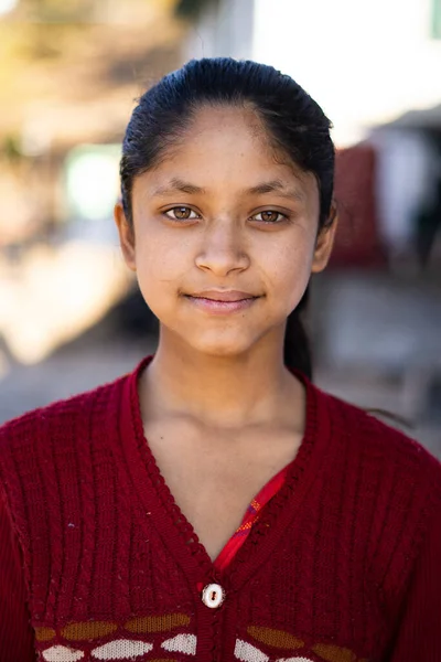 Portrait of a young indian village girl wearing winter clothes and smiling into the camera.