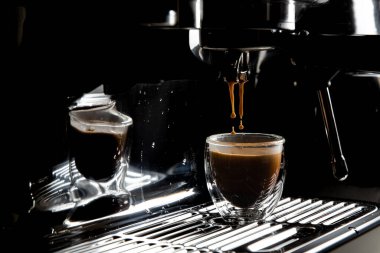 Koyu kahve damlaları şeffaf cam bir espresso bardağına damlıyor. Elle yapılan espresso makinesinde fotokopi alanı var.