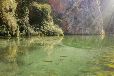 Çok güzel bir kristal göl manzarası var. Sağ üstte güneş ışınları var.