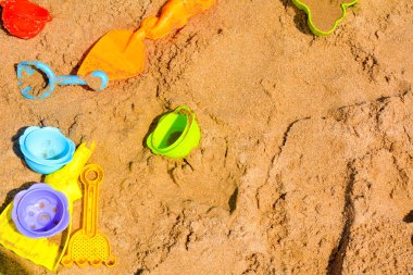 Sahilde güzel renkleri olan kum oyuncakları, sarı, mavi, turuncu, mor, yeşil, fotoğrafın sol tarafında.