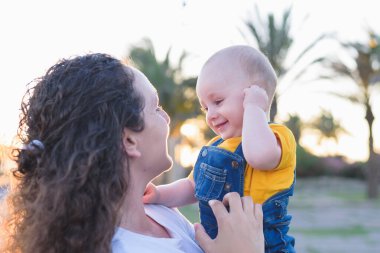 Anne ve kızı gün batımında buğday tarlasında ormanın yanında yürüyorlar.