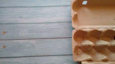 Bir kadının eli yumurta kutusundan bej bir yumurta alır.