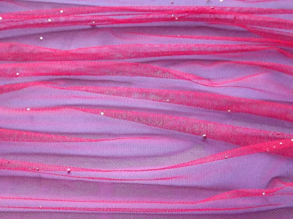 Tul rosa en un pliegue sobre un fondo púrpura como telón de fondo — Foto de Stock