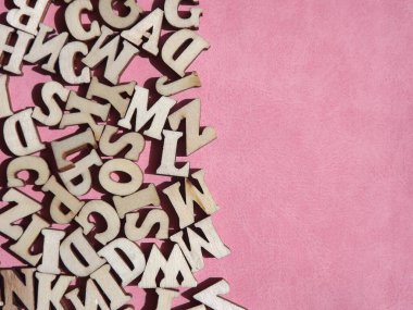 Arkaplan olarak pembe süet üzerine İngiliz alfabesinin ahşap harfleri