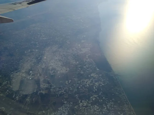 Blick aus dem Flugzeugfenster auf die Küste und Wolken — Stockfoto