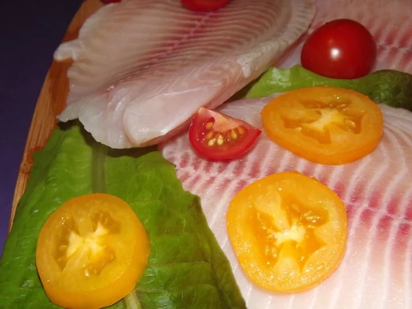 Processen för tillagning av tilapia fiskfilé med tomater, oliver och salladsblad — Stockfoto