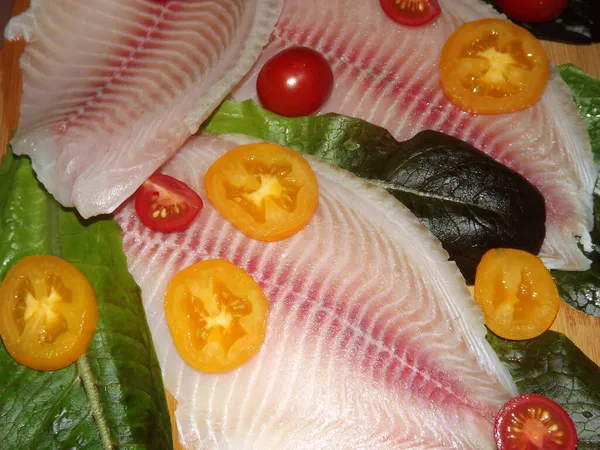 El proceso de cocción del filete de tilapia con tomates, aceitunas y hojas de lechuga — Foto de Stock