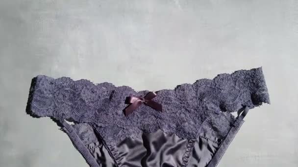 Bragas eróticas azules oscuras hechas de seda y guipure de cerca sobre un fondo gris — Vídeos de Stock