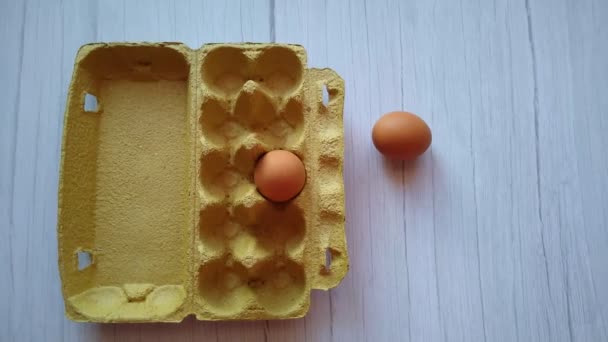 Een vrouwenhand neemt een beige ei uit een eierdoos — Stockvideo