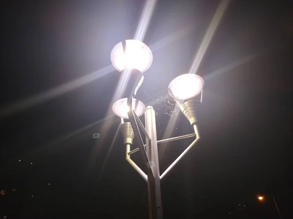 Cobweb on top of a lamppost between three lanterns at night — Stock Photo, Image
