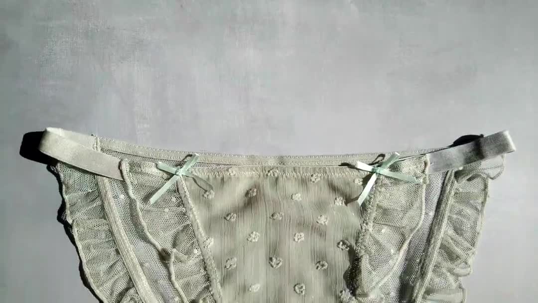 Světle zelené dámské kalhotky s volánky na šedém pozadí zblízka — Stock video