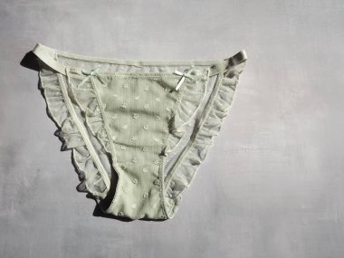 Açık yeşil kadın külotu ve gri bir arka planda fırfırları var.