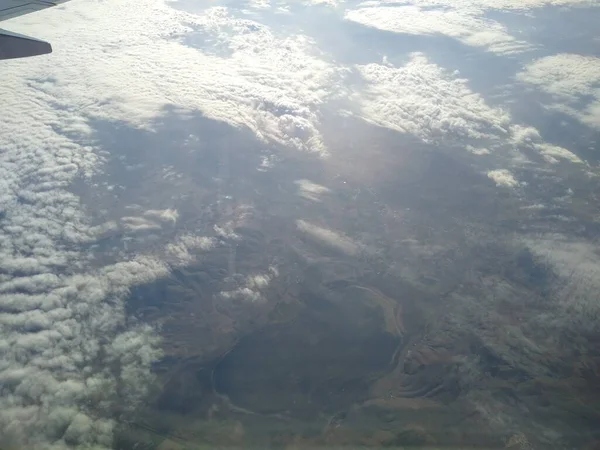 Zicht vanuit het raam van het vliegtuig op de kustlijn en wolken — Stockfoto