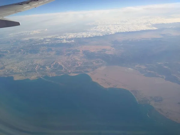 Vista desde la ventana del avión en la costa y las nubes — Foto de Stock